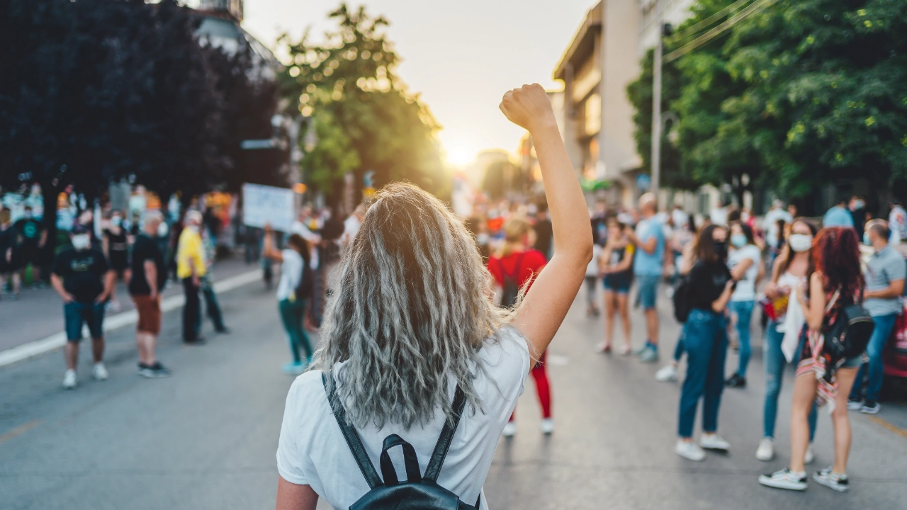 Frau mit erhobener Faust protestiert auf der Straße.