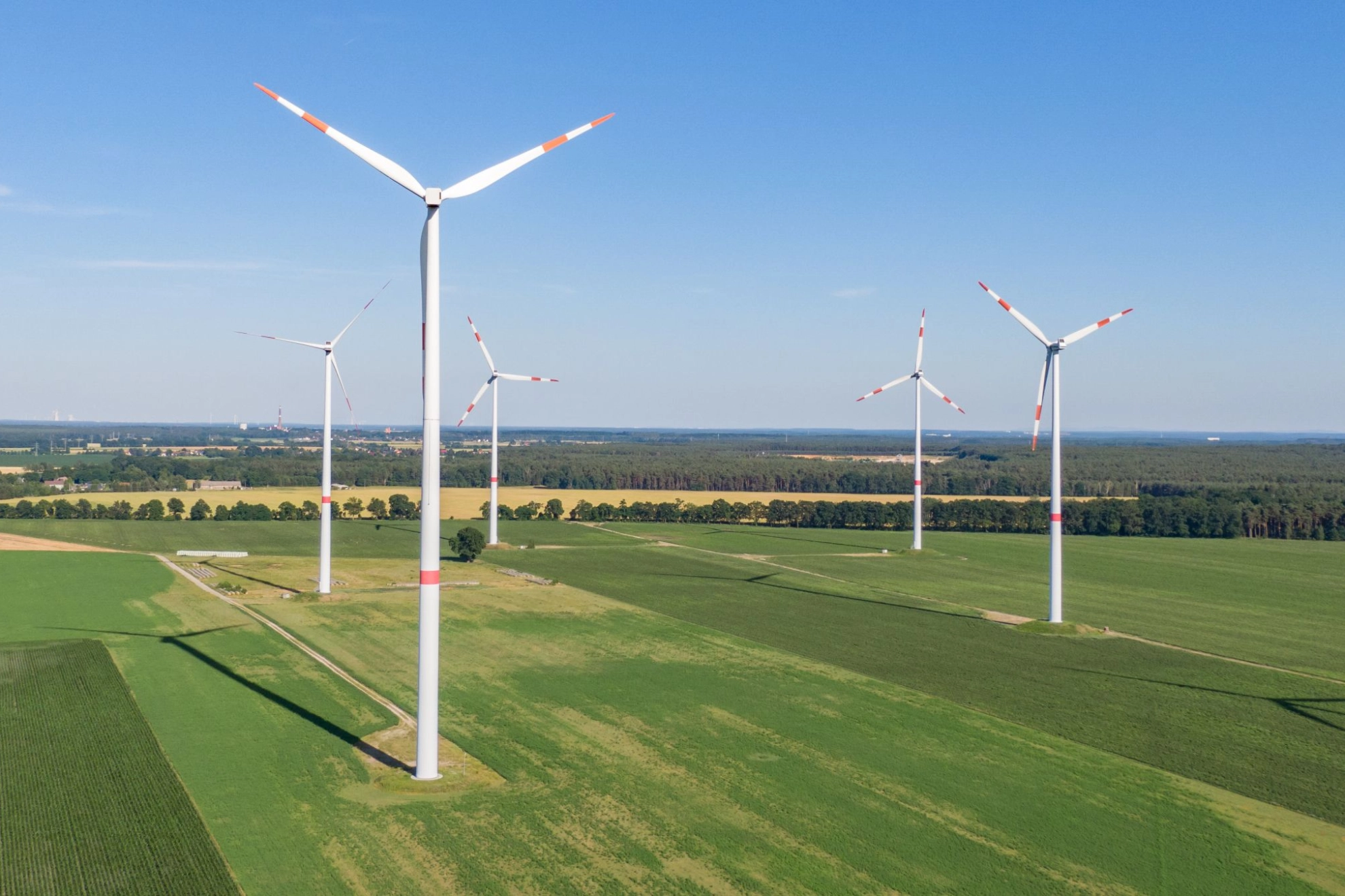 mehrere Windkraftanlagen bei gutem Wetter auf grüner Wiese