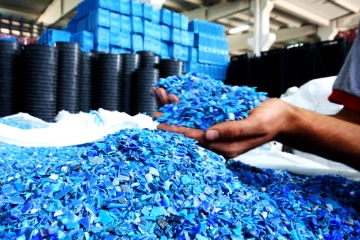 Eine Hand hält blaues Kunststoffgranulat.